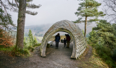 Family of two adults and two children inside Pine Cone Point viewing shelter, Craigvinean Forest, Dunkeld