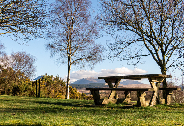 A picnic table on a grassy hill with mountains behind