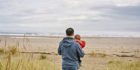 Rear view of man carrying small boy as they walk out to sea shore, Tentsmuir beach , near Leuchars