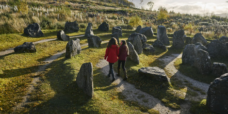 Rear view of woman in red jacket and teenage girl walking through Touchstone Maze, labyrinth of Scottish stones, Blackmuir Wood, near Strathpeffer