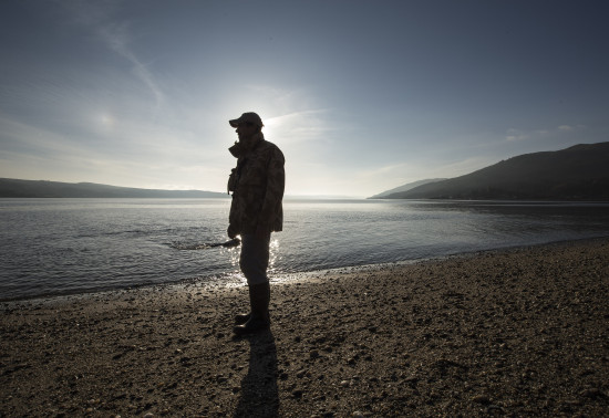 A man stands along the beach at sunset