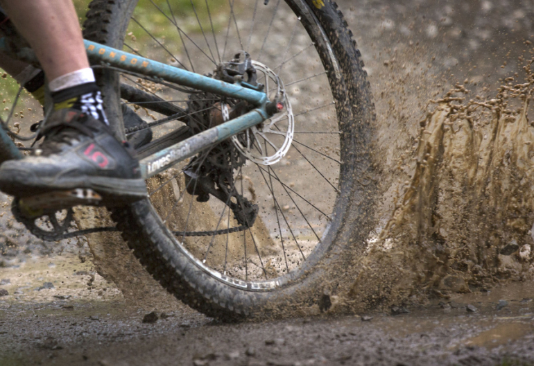 Close up of a mountain biker's rear wheel going through a puddle