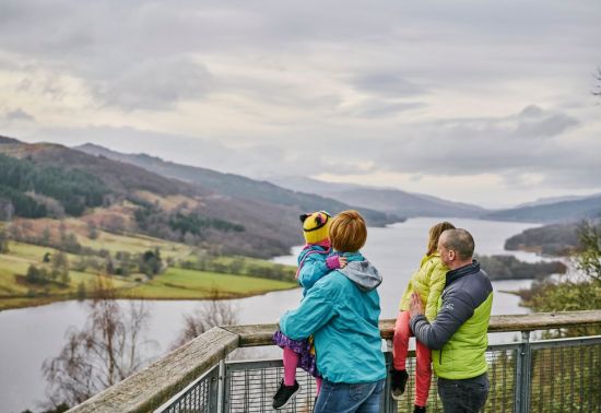 a family standing on a view point looking down a loch