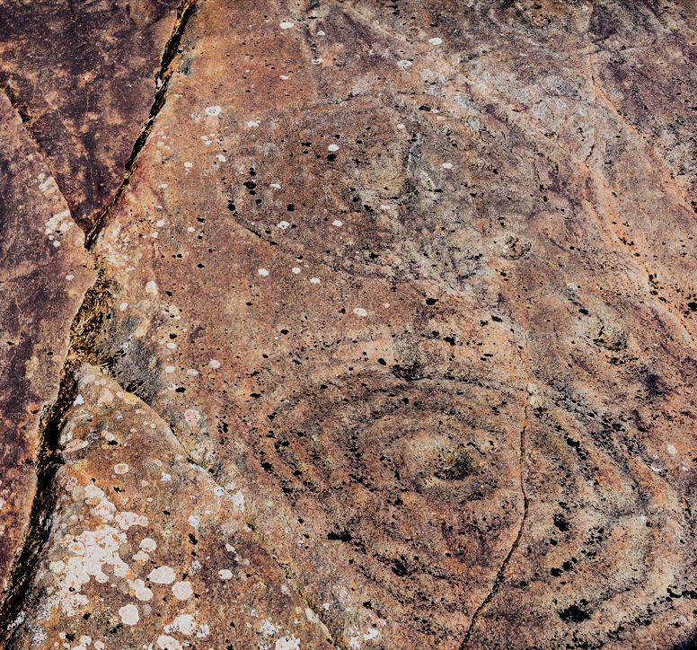 Close-up of red sandstone rock with ancient cup and ring engravings
