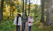 A man, woman and teenage girl walking along tree lined woodland path, Aldie Burn forest, near Tain