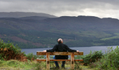 Man takes in view over Loch Ness, from wooden bench at Allt na Criche, near Fort Augustus