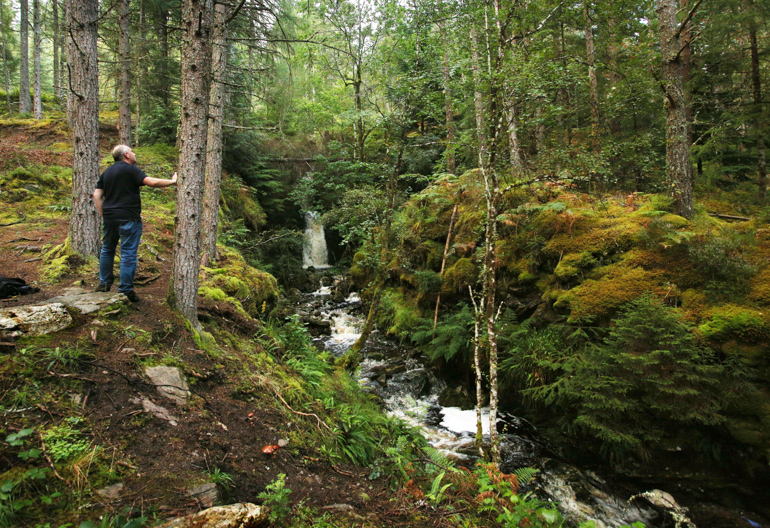 Male walker looking at view of waterfall, Allt na Criche, near Fort Augustus
