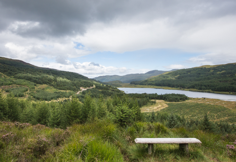 View of loch and hills from site of ruined Highland Clearance village of Aoineadh Mor with a bench infront