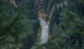 Aerial view of motorway though dense forest of conifers, Ardgartan, Argyll Forest Park