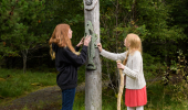 Two young girls inspect wooden totem pole, Borgie Glen, Sutherland