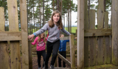 Two young girls and young boy playing in Natural Play Area, Camore Wood, Dornoch, Sutherland