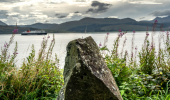 A stone wall with a single stone structure and the Isle of Mull behind it