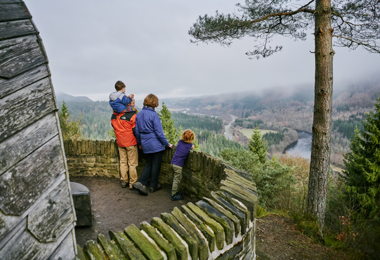 Family of two adults and two children admire view from Pine Cone Point, Craigvinean Forest, Dunkeld