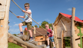 Two young boys climbing up to tree house at adventure play park, Falls of Shin, by Lairg, Sutherland