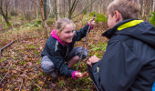 A boy and girl look at wildlife on the woodland floor