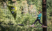 A woman balances on wires above forest at GoApe Treetop Adventures
