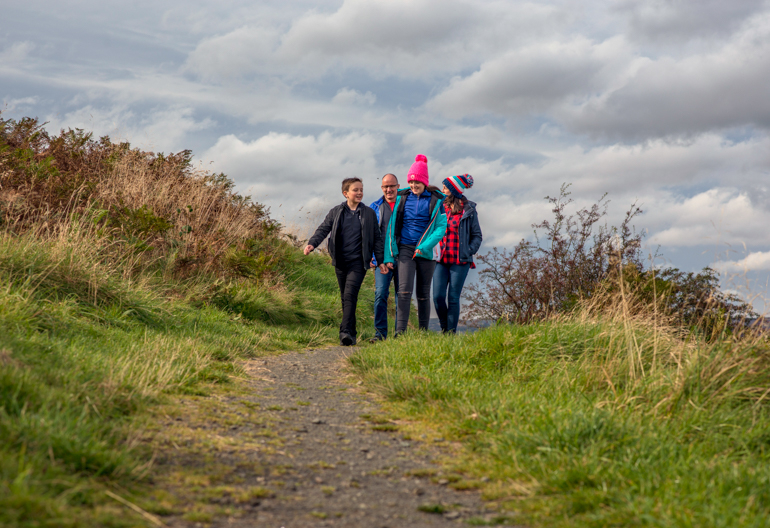 A family of four walking along a countryside footpath