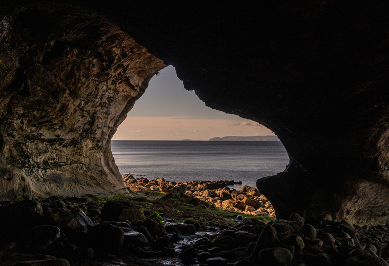 Inside of a cave looking at the sea