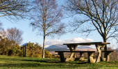 A picnic table on a grassy hill with mountains behind