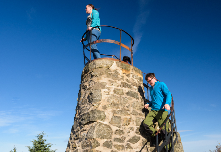 Two people at a narrow stone lookout tower