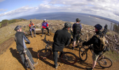 A group of mountain bikers look out to sea from a hilltop