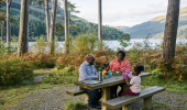 A family of four sit at a woodland picnic table