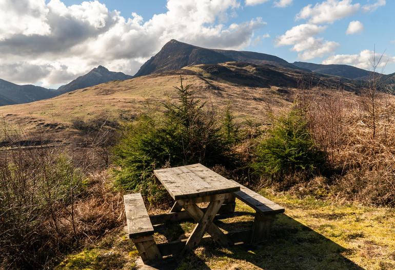 A picnic table on a hillside next to a mountain