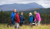 Male and female walkers with dog on hillside at Rosal, Strathnaver, with Ben Loyal mountain in background, Sutherland