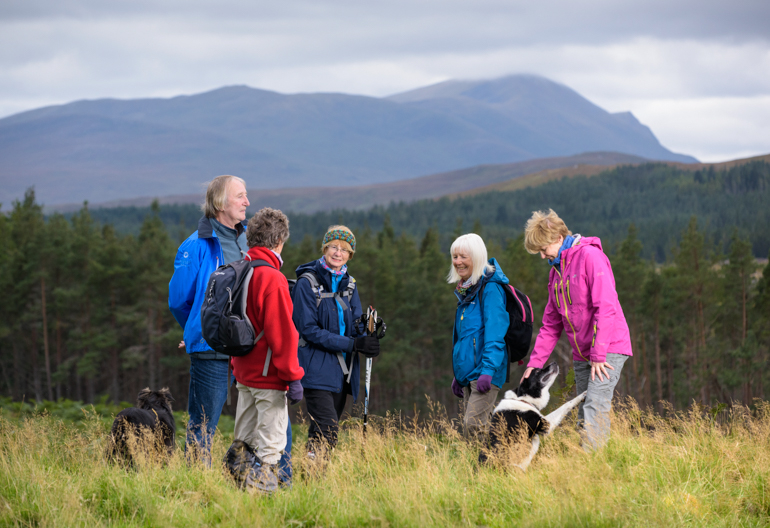 Male and female walkers with dog on hillside at Rosal, Strathnaver, with Ben Loyal mountain in background, Sutherland