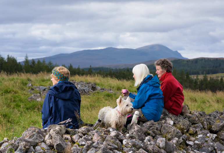 Three female hikers, with dog, take a break at ruins of clearance township of Rosal, Strathnaver, Sutherland