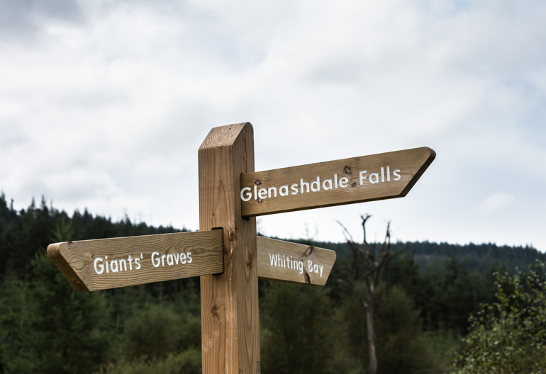 A finger post sign points in the direction of Giants' Graves, Glenashdale Falls and Whiting Bay