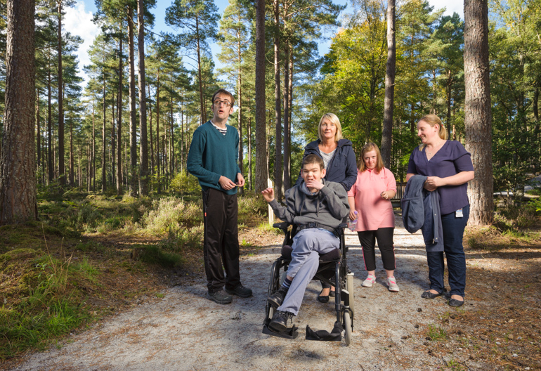 Group of carers and clients (in wheelchairs) pose in picnic spot, Torrieston, near Elgin, Moray