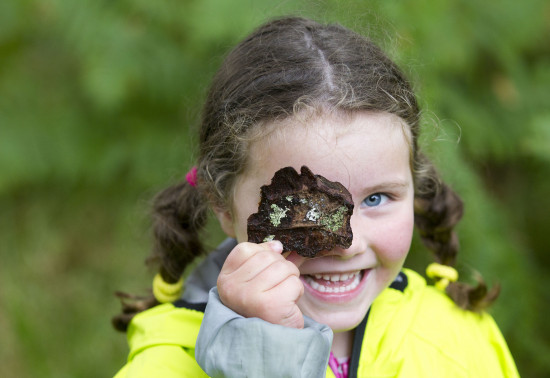 Girl holding a lichen-covered leaf to her eye