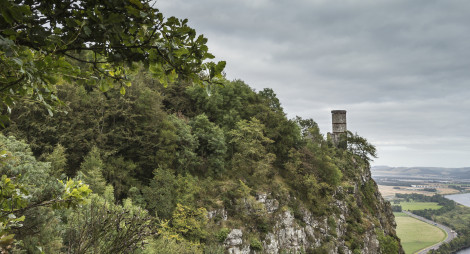 A distant view of Kinnoull Tower at Kinnoull Hill in Perthshire, with trees, cliffs and the River Tay visible.