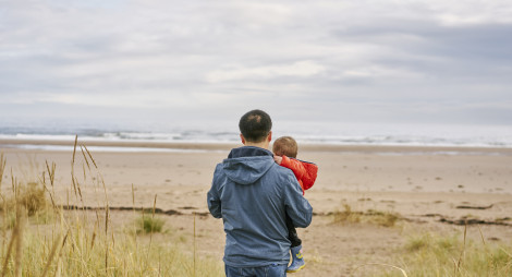 Rear view of man carrying small boy as they walk out to sea shore, Tentsmuir beach , near Leuchars