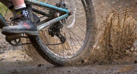 Mountain bike wheel splashing through muddy puddle