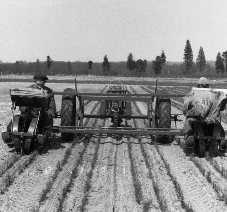 Black and white image of antiquated tractor in ploughed field
