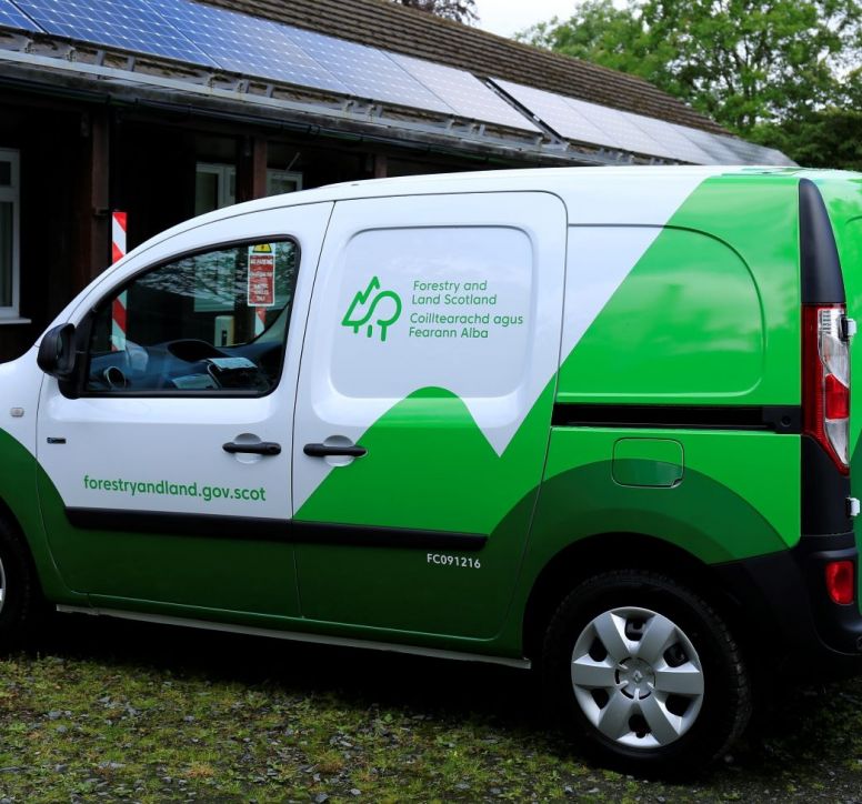 Green and white electric van parked up to charge