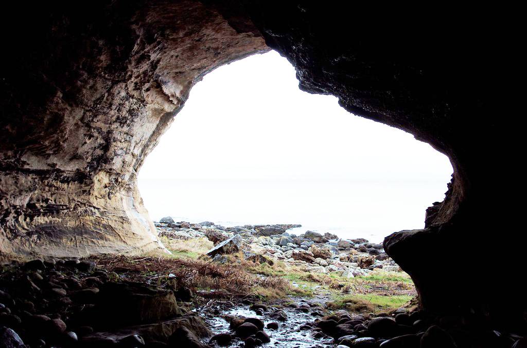 View out of a large sea cave showing sky beyond and rocks near the entrance