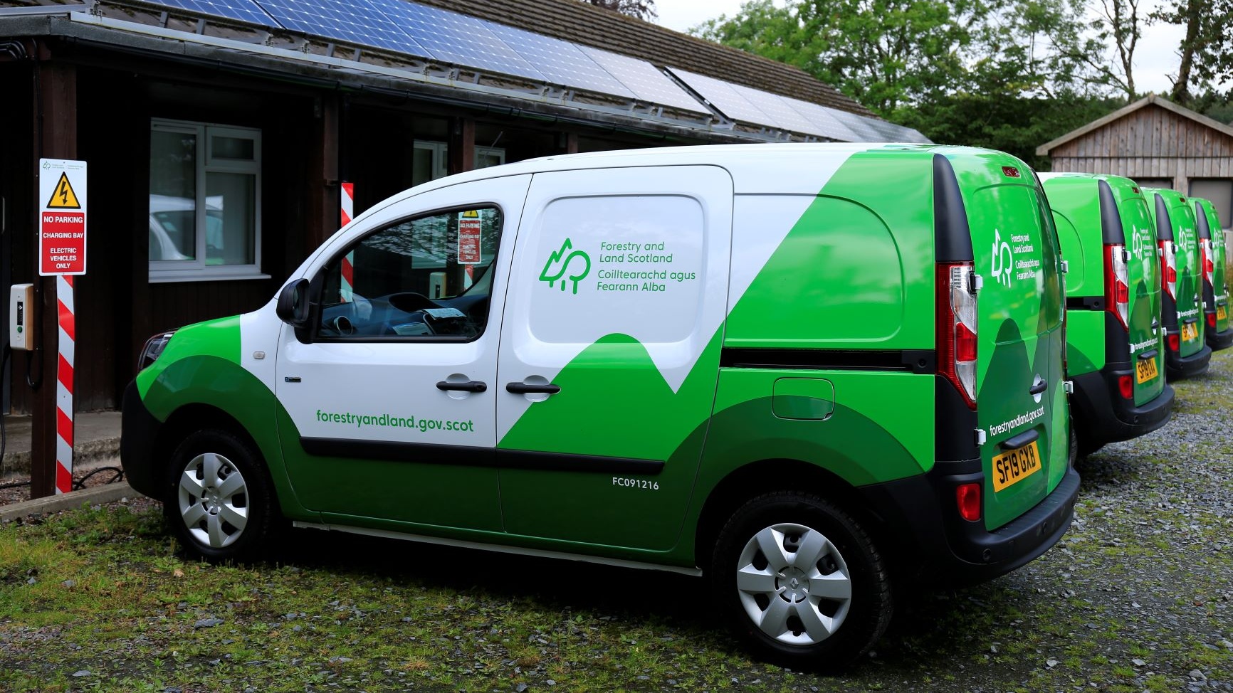 FLS branded electric vehicle in green and white at a charging station