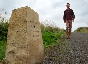 A man walking towards a carved marker stone