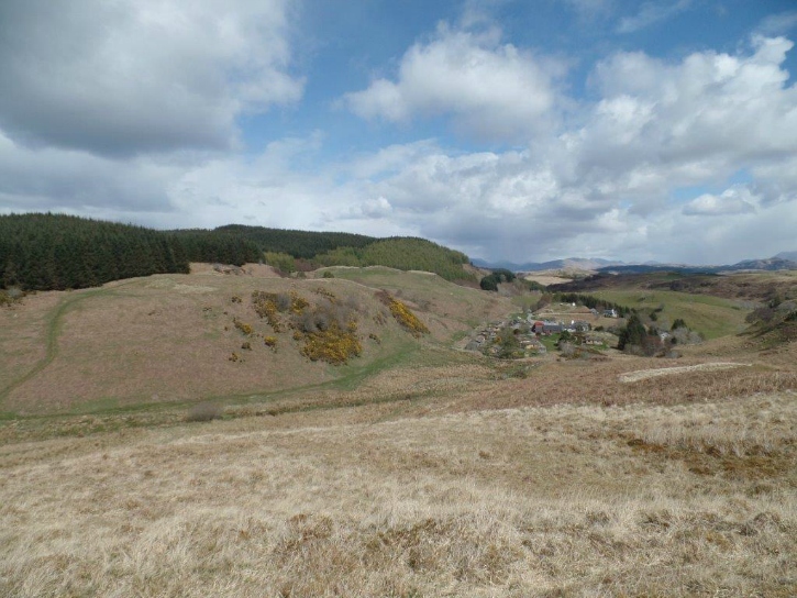 Rough moorland below a forested hilltop
