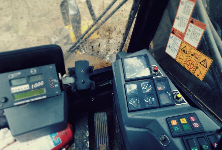 Inside view of a forest harvester's cab showing several buttons and dials