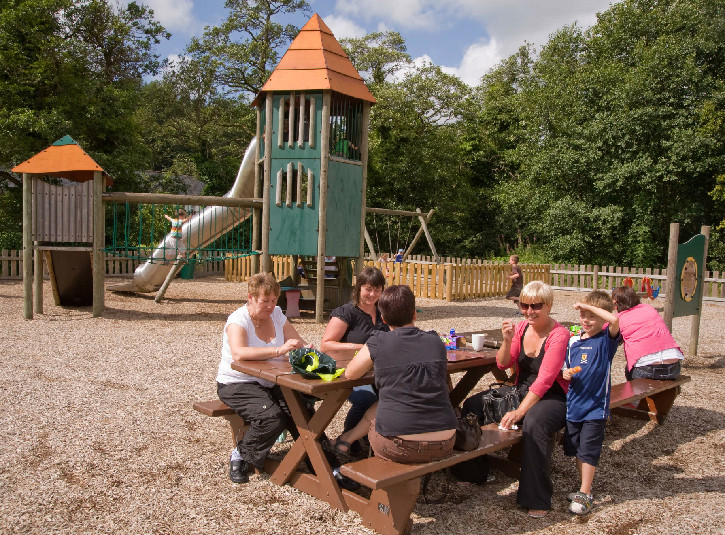 A family gathered round a picnic table in a playpark