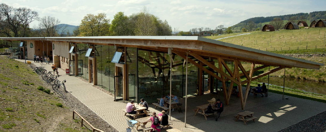 Outdoor visitor centre with wooden and glass construction situated among grassy fields and trees