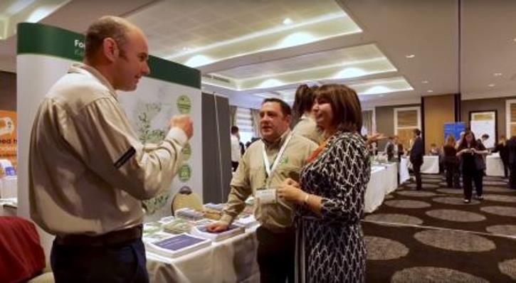 Several people gathered talking at a conference event with different booths and stalls
