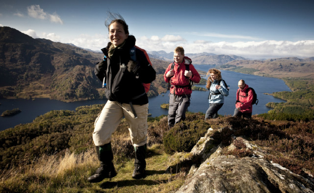 Family walking up a hill above a loch