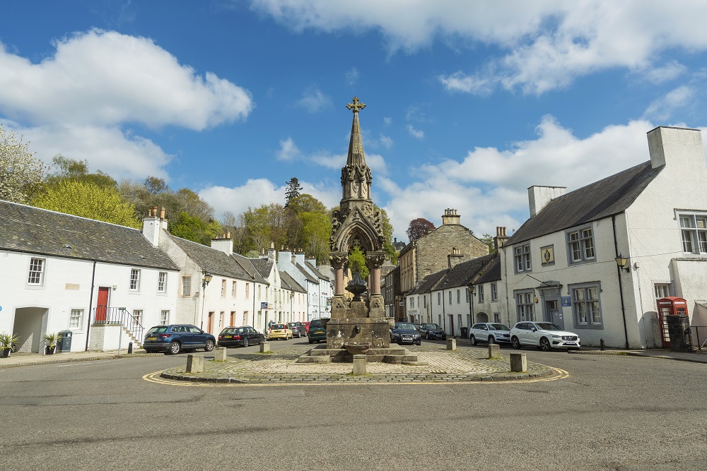 A sandstone monument surrounded by white painted houses in the village of Dunkeld