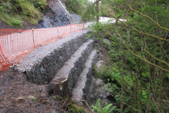 Construction on a forest road with red safety netting 