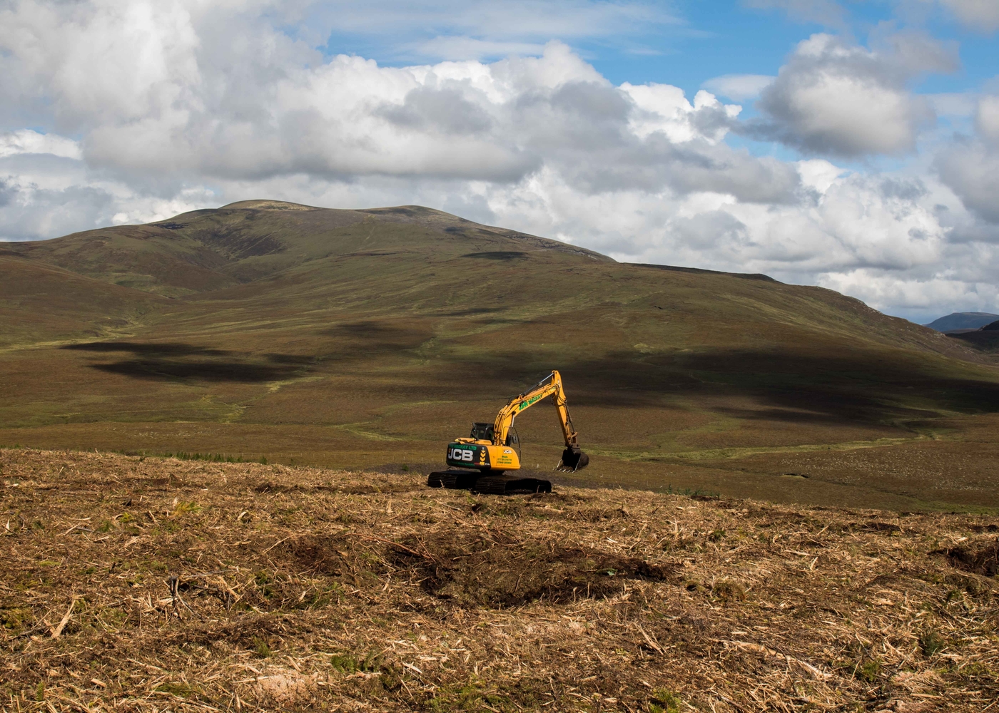 A yellow machine in a peatland with blue skies